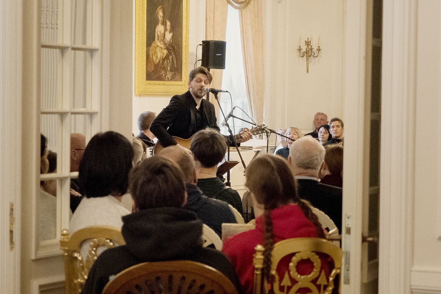 Justinas Stanislovaitis dainuoja ir groja gitara prieš sėdinčią publiką